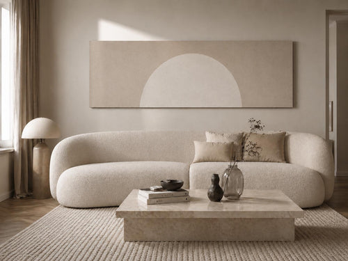 May include: A long, rectangular wall art piece featuring a large, pale beige semi-circle against a muted taupe background. The artwork is displayed above a curved, cream-colored textured sofa, a low stone coffee table, and a tall, rounded floor lamp.